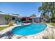 Beautiful backyard featuring an in-ground pool, lounge seating, and lush tropical landscaping at 1503 Albemarle Ct, Dunedin, FL 34698