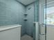 Beautiful tile shower with glass door features built-in shelves and updated fixtures at 1503 Albemarle Ct, Dunedin, FL 34698
