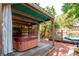 Backyard retreat featuring a hot tub under a charming gazebo with privacy curtains, adjacent to a pool deck at 1514 Florida Ave, Palm Harbor, FL 34683