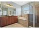 Spa-like bathroom features a soaking tub, glass-enclosed shower, and double vanity sinks at 15711 Starling Dale Ln, Lithia, FL 33547