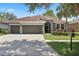 Lovely home showcasing well-manicured landscaping, a three-car garage, and a gray stucco exterior at 15711 Starling Dale Ln, Lithia, FL 33547