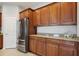 Elegant kitchen featuring granite countertops, wood cabinets, and stainless steel refrigerator at 15711 Starling Dale Ln, Lithia, FL 33547