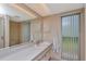 Bathroom featuring a wide vanity, large mirror, white cabinets, and window with vertical blinds at 1907 Sandpiper Dr, Clearwater, FL 33764