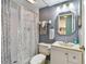 A well-lit bathroom with a shower, toilet, sink, vanity, and octagon mirror at 19925 Gulf Blvd # 105, Indian Shores, FL 33785