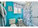 Well-lit bathroom with blue walls, toilet, window, and a shower with a floral patterned curtain at 19925 Gulf Blvd # 105, Indian Shores, FL 33785