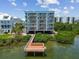 Beautiful waterfront condo building featuring multiple balconies, a private dock, and lush surroundings at 19925 Gulf Blvd # 105, Indian Shores, FL 33785