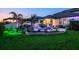 Beautiful backyard at dusk with a pool, water features, palm trees, and an outdoor kitchen at 21874 Crest Meadow Dr, Land O Lakes, FL 34637