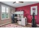 Bedroom features a white desk with storage, pink accent wall, and natural light from a window with shutters at 21874 Crest Meadow Dr, Land O Lakes, FL 34637