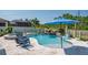 Inviting backyard pool with waterfall feature, stylish patio, and relaxing lounge chairs under a bright blue umbrella at 21874 Crest Meadow Dr, Land O Lakes, FL 34637