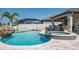 Lovely backyard pool with attached hot tub, rock waterfall, and blue umbrella on a sunny day at 21874 Crest Meadow Dr, Land O Lakes, FL 34637