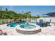 Beautiful backyard pool with spa and waterfall features, surrounded by lush landscaping and comfortable lounge seating at 21874 Crest Meadow Dr, Land O Lakes, FL 34637