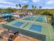 Aerial view of multiple pickleball courts fenced in a community setting with palm trees and nearby club at 2407 Kensington Greens Dr, Sun City Center, FL 33573