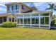 Back of the house featuring a sunroom with views of the lawn and tropical foliage at 2407 Kensington Greens Dr, Sun City Center, FL 33573