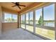 Bright sunroom with a ceiling fan and multiple windows overlooking a lush green yard and a serene lake at 2407 Kensington Greens Dr, Sun City Center, FL 33573