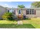 Charming front entrance with a wooden porch, complemented by decorative shutters and a palm tree at 26438 Glenwood Dr, Wesley Chapel, FL 33544
