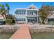Waterfront home featuring a patio with outdoor seating, a private dock, and direct water access on a sunny day at 2903 Pass A Grille Way, St Pete Beach, FL 33706