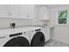 Clean, all-white laundry room with modern washer and dryer, sink, and plenty of cabinet space at 2903 Pass A Grille Way, St Pete Beach, FL 33706