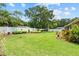 A large backyard with green grass, mature trees, white fence, and a small outbuilding at 3041 Colonial Ridge Dr, Brandon, FL 33511