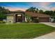 Charming single-story home featuring a manicured lawn and a welcoming front entrance with red door and arched portico at 3041 Colonial Ridge Dr, Brandon, FL 33511