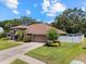 Single-story home with attached garage and fenced yard, complemented by mature trees and landscaping at 3041 Colonial Ridge Dr, Brandon, FL 33511
