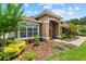 Home with an arched portico, striking red door, and neat lawn, bordered by colorful landscaping and green trees at 3041 Colonial Ridge Dr, Brandon, FL 33511