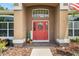 Charming entryway features a red front door with decorative wreath and sidelights, complemented by lush landscaping at 3041 Colonial Ridge Dr, Brandon, FL 33511