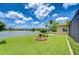 Private backyard with mature landscaping, a small garden feature, and a white picket fence overlooking the lake at 3123 Whitehead Ln, Land O Lakes, FL 34638