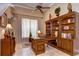 An elegant office featuring custom built-in wood shelving, a large desk, and a neutral color palette at 3123 Whitehead Ln, Land O Lakes, FL 34638