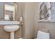 A quaint powder room featuring an elegant mirror, pedestal sink, and decorative artwork at 3123 Whitehead Ln, Land O Lakes, FL 34638