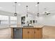 Island features a stainless steel dishwasher, wood cabinets, sink with gooseneck faucet, and modern pendant lighting at 33487 Azalea Ridge Dr, Wesley Chapel, FL 33545