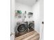 A modern laundry room with stainless steel washer and dryer with wire rack and storage at 35552 Shade Fern Ln, Zephyrhills, FL 33541