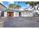 Stylish white single-story home with a gated entrance, dark roof, wooden garage door and a spacious driveway at 3800 Shore Acres Ne Blvd, St Petersburg, FL 33703
