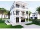 Three-story white home with dual balconies, a garage, and meticulously landscaped front yard at 3800 Shore Acres Ne Blvd, St Petersburg, FL 33703