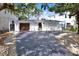 Charming single-story home with a gated entrance, dark roof, wooden garage door, and an expansive driveway at 3800 Shore Acres Ne Blvd, St Petersburg, FL 33703