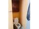 Cozy half bathroom featuring a toilet with brown cabinets above at 5805 Tennessee Ave, New Port Richey, FL 34652