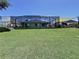 Lush backyard with mature lawn and shade sails by a screened-in pool, ideal for outdoor activities at 6205 Chapel Pines Blvd, Wesley Chapel, FL 33545