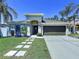 Charming single-story home with a well-manicured lawn, palm trees, and a two-car garage at 6205 Chapel Pines Blvd, Wesley Chapel, FL 33545