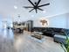 The large living room has wood floors, an open concept to the kitchen, and a gray couch with seating for the Gathering at 6205 Chapel Pines Blvd, Wesley Chapel, FL 33545