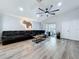 Spacious living room with gray L shaped couch, wood floors, a stylish ceiling fan, and sliding glass doors at 6205 Chapel Pines Blvd, Wesley Chapel, FL 33545