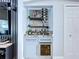This wet bar includes granite countertops, gray shaker cabinets, a wine fridge, and shelving for liquor and glasses at 6205 Chapel Pines Blvd, Wesley Chapel, FL 33545