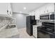 This kitchen features white cabinets, a black refrigerator and range, and granite countertops and backsplash at 7123 Cherry Laurel Dr, Port Richey, FL 34668
