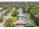 An aerial view of a single-Gathering home with a screened-in pool, lush green lawn, and mature trees at 734 Lake Forest Rd, Clearwater, FL 33765