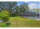 Lush backyard featuring a screened-in pool area surrounded by well-maintained lawn and mature trees at 734 Lake Forest Rd, Clearwater, FL 33765