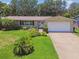 Welcoming single-story home featuring a manicured lawn, mature landscaping, and a two car garage at 734 Lake Forest Rd, Clearwater, FL 33765