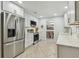 Well-lit kitchen with stainless steel refrigerator, white cabinets, and open view to the dining room at 734 Lake Forest Rd, Clearwater, FL 33765