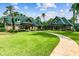 Two clubhouse buildings are surrounded by a lush green lawn, tall trees and a sidewalk in this community setting at 7410 Ambleside Dr, Land O Lakes, FL 34637