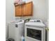 Laundry room with wood cabinets, a white washer and dryer, and a laundry basket on top of the washing machine at 7410 Ambleside Dr, Land O Lakes, FL 34637