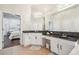 Bright bathroom features double sinks with dark countertops and white cabinets at 7410 Ambleside Dr, Land O Lakes, FL 34637