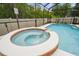A blue pool with a built-in brick hot tub offers relaxation and recreation for Gathering and guests at 7410 Ambleside Dr, Land O Lakes, FL 34637
