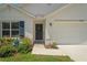Up close view of the front entrance with blue shutters, a manicured garden, and a two-car garage at 8508 Bay Dr, Spring Hill, FL 34606